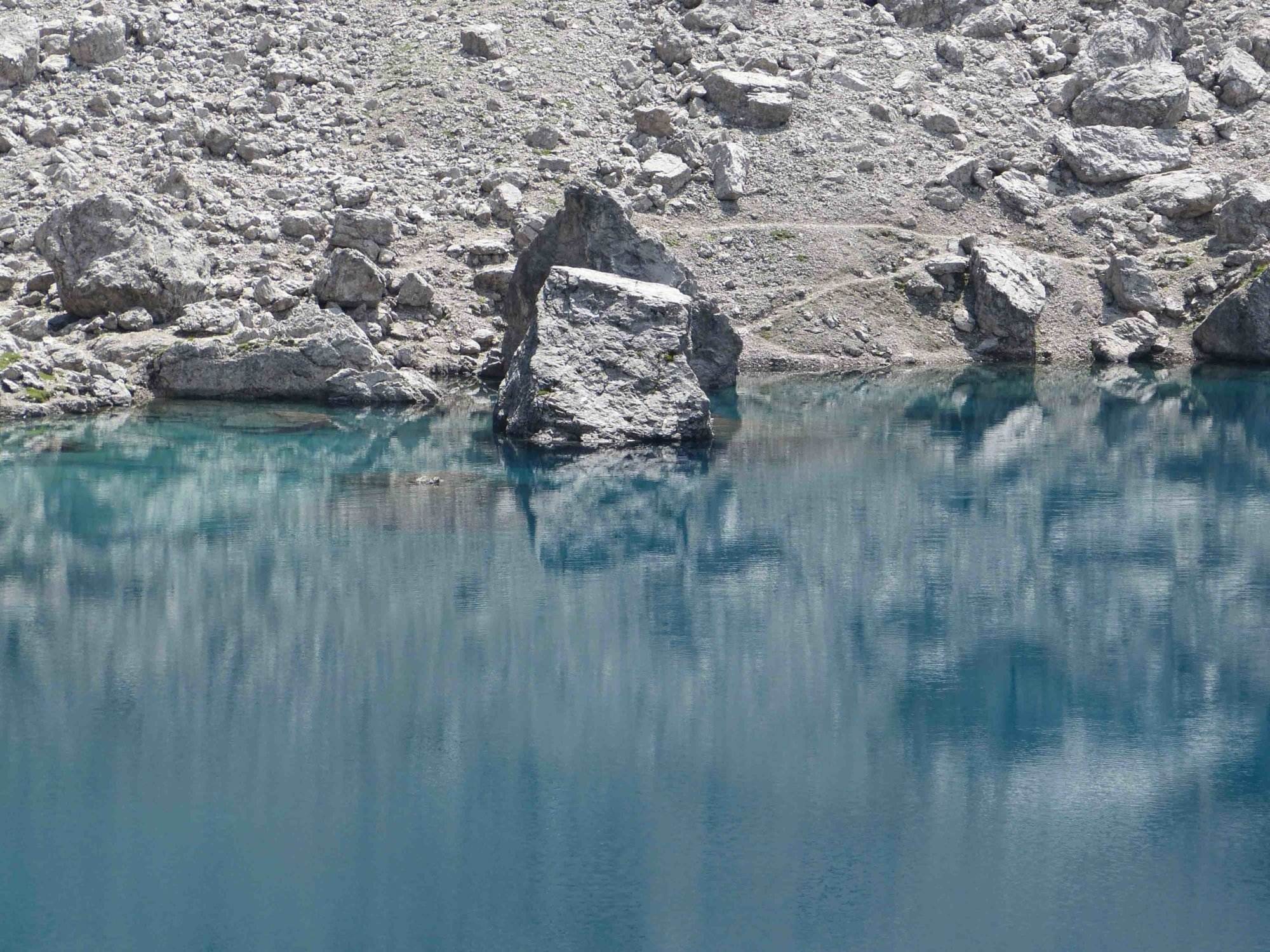 Ein Mann steht in einem von Felsen umgebenen See in den Lienzer Dolomiten.