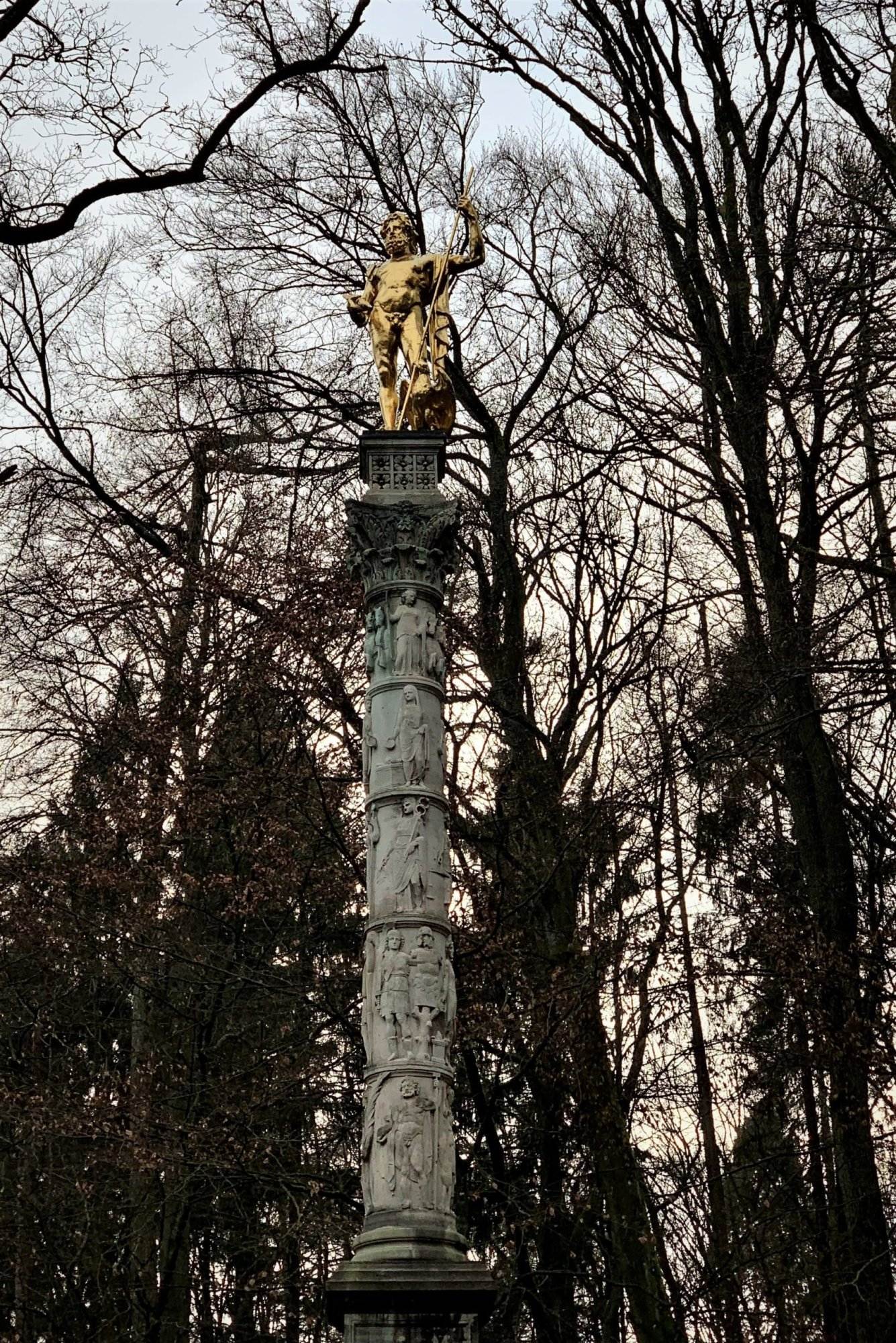 Eine Statue steht auf einer Säule in einem Park.