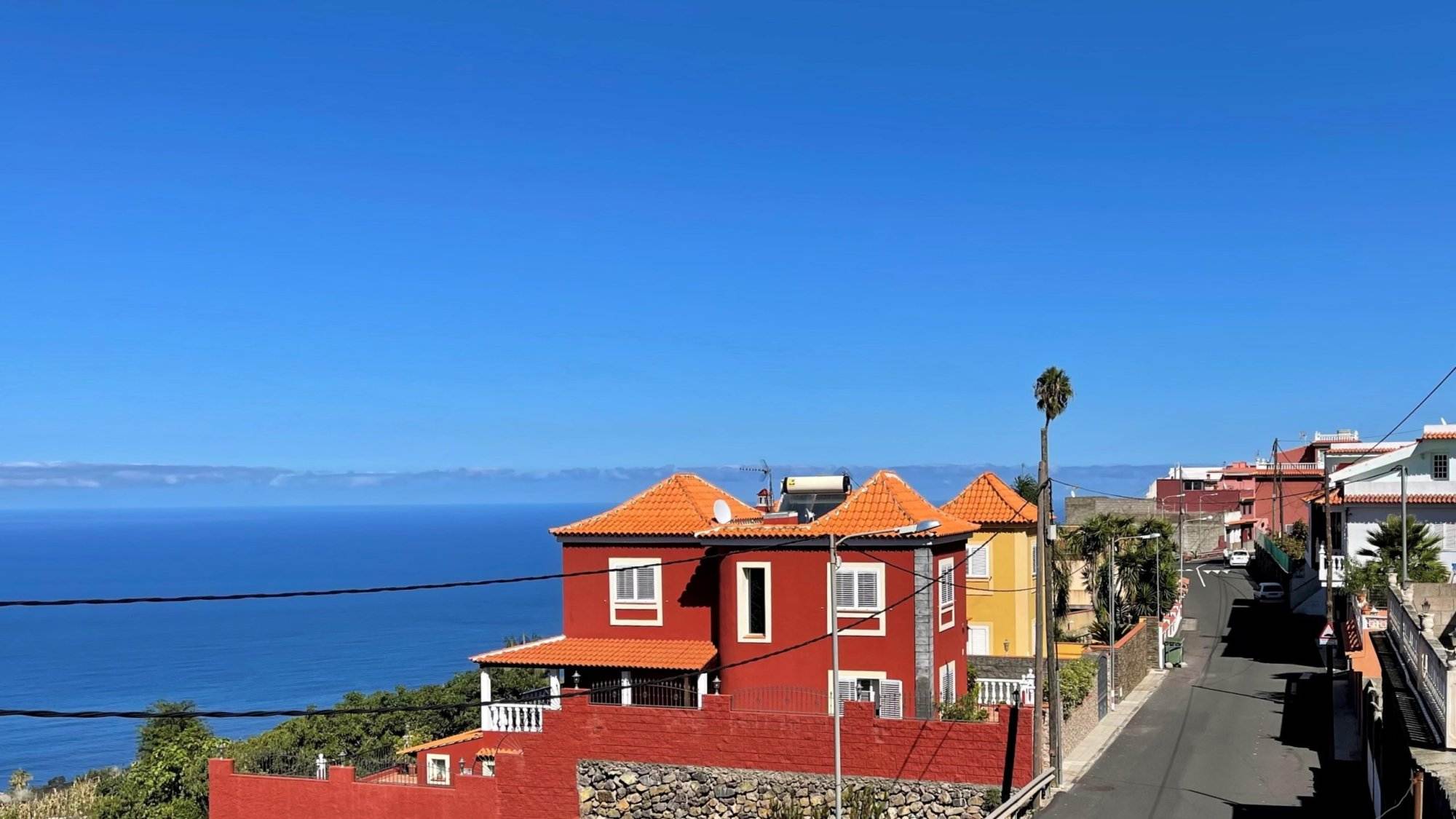 Eine Straße mit roten Häusern und Blick auf das Meer.