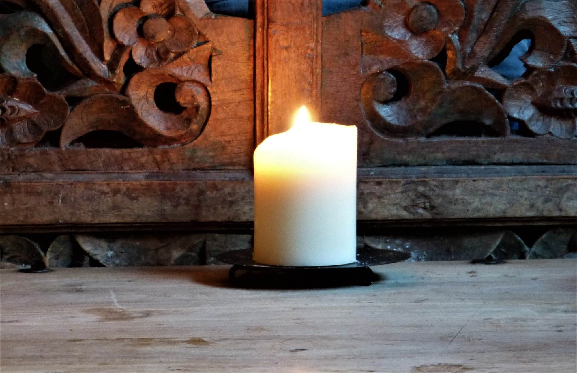 Auf einem Holztisch steht eine Kerze.