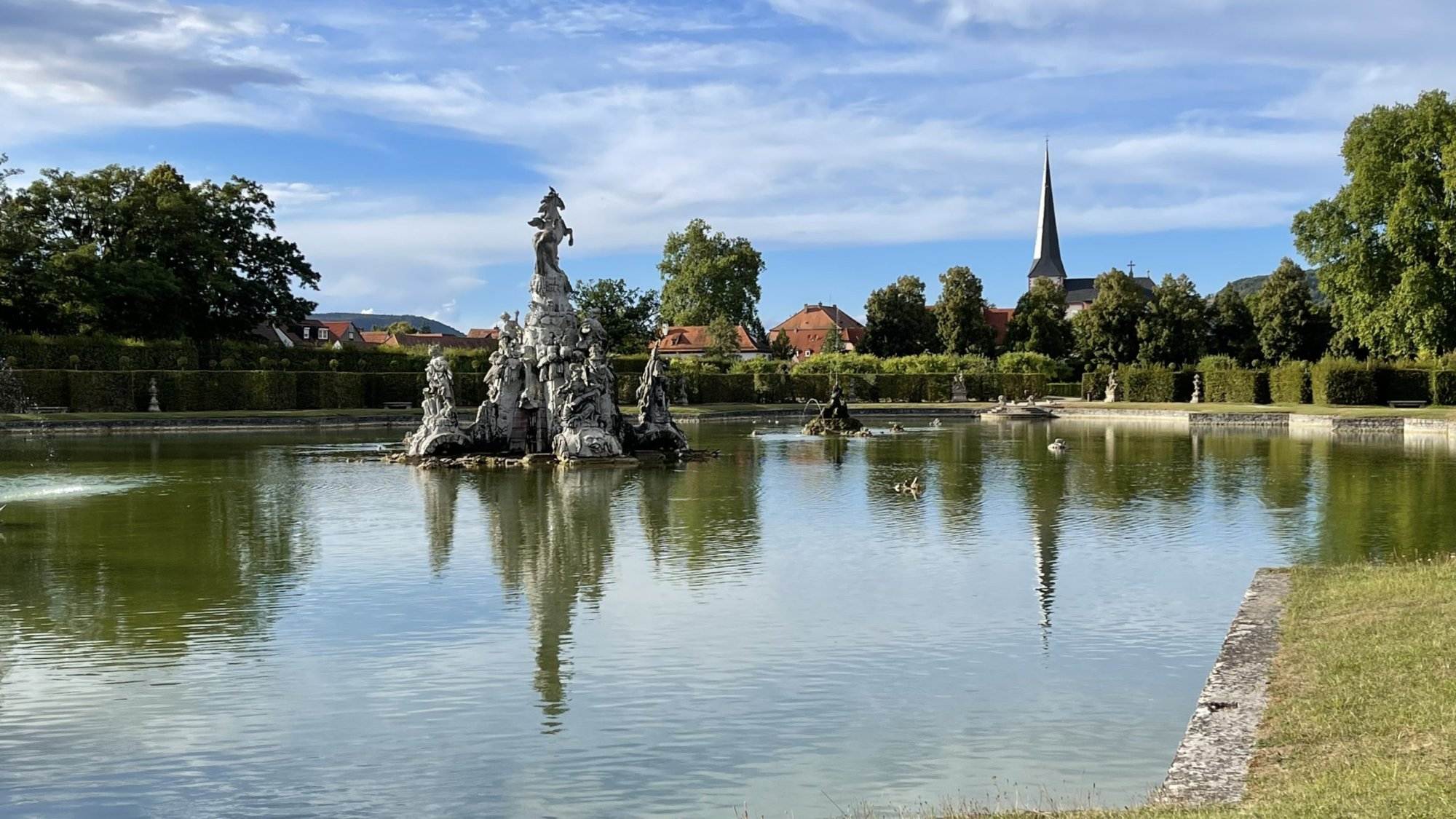 Ein Teich mit einer Statue in der Mitte.