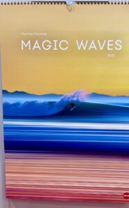 Kalendercover mit einer lebendigen Meereslandschaft bei Sonnenuntergang mit einem Surfer auf einer Welle. Der Titel lautet „Magic Waves 2025“ von Thomas Fotomas.